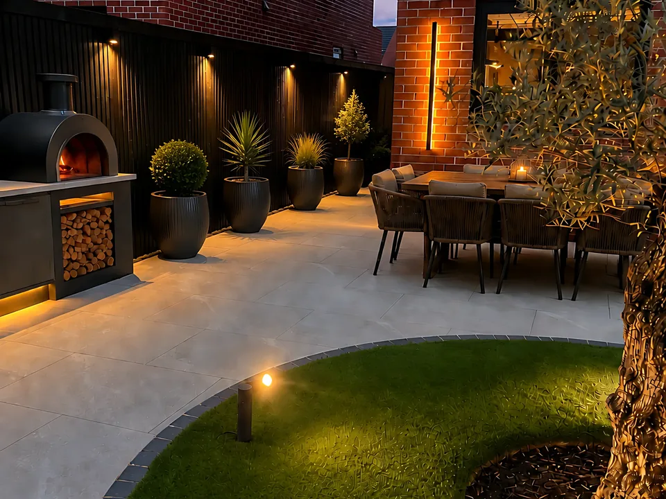 Contemporary garden with porcelain paving, olive tree and layered lighting